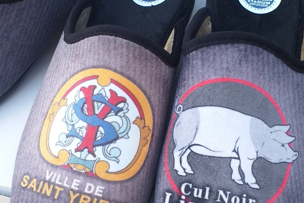 Des mules et pantoufles style « charentaise »,avec le logo de la ville de Saint-Yrieix-la-Perche.
